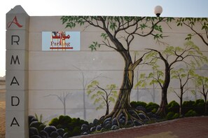 Paredes com um grande mural de árvore e uma placa indicando estacionamento.