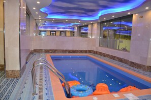 A swimming pool with a glass barrier, blue and orange pool floats, and a metal ladder. - Golden New Armada (Jizan)