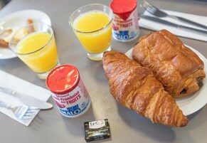 Desayuno con cruasanes, jugo y un pequeño recipiente de yogur.