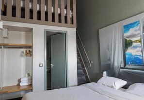 A hotel room with a bed, a window with a view of a river, a door leading to a bathroom, and a staircase. - B&B Hotel Orleans Ouest La Chapelle-saint-mesmin (La Chapelle-Saint-Mesmin)