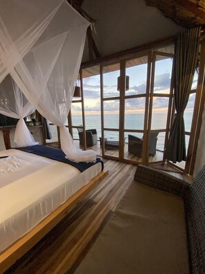 Una habitación con una cama, un ventanal y vistas al mar.