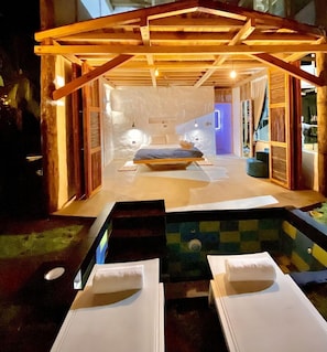 A bedroom with a bed, bedside tables, and a view of the outside. - RCH Luxury Hotel & Pool (Dibulla)