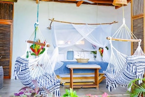 A room with a bed, a table, and two hanging hammocks. - RCH Luxury Hotel & Pool (Dibulla)