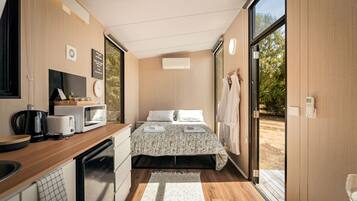 Une pièce de taille modeste comprenant un lit, une kitchenette et une grande fenêtre.