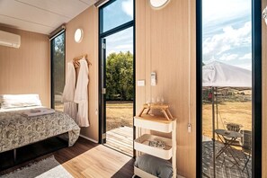 A modern bedroom with a large bed, a wooden wardrobe, and a view of the outdoors.