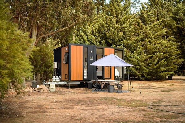 A modern, compact cabin with a large window, a dining table, and an umbrella.