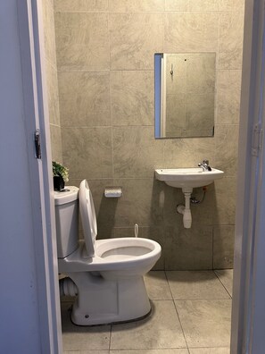 A bathroom with a toilet, sink, and mirror. - Cynthia’s Gateway with a Swimming Pool – Stylish & Serene Stay (Nairobi)