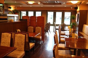 Interior de restaurante con muebles de madera, una zona de bar y amplios ventanales.