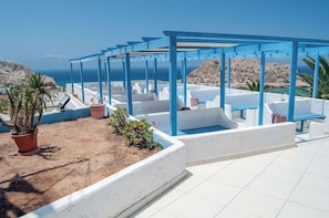 A rooftop terrace with a blue pergola, white walls, and potted plants. - Bluu Bahari Hotel (Karpathos)