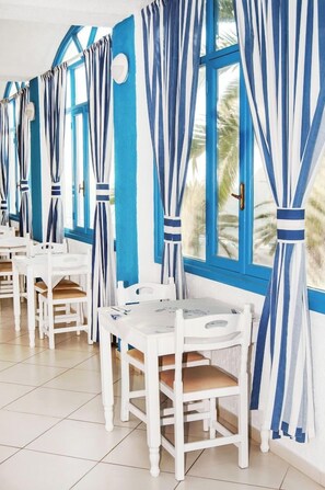 Una habitación con muebles blancos, cortinas azules y vistas a palmeras.