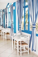 Una habitación con muebles blancos, cortinas azules y vistas a palmeras.