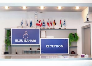 Un área de recepción con un letrero que dice 'BLUU BAHARI' y varias banderas a la vista.
