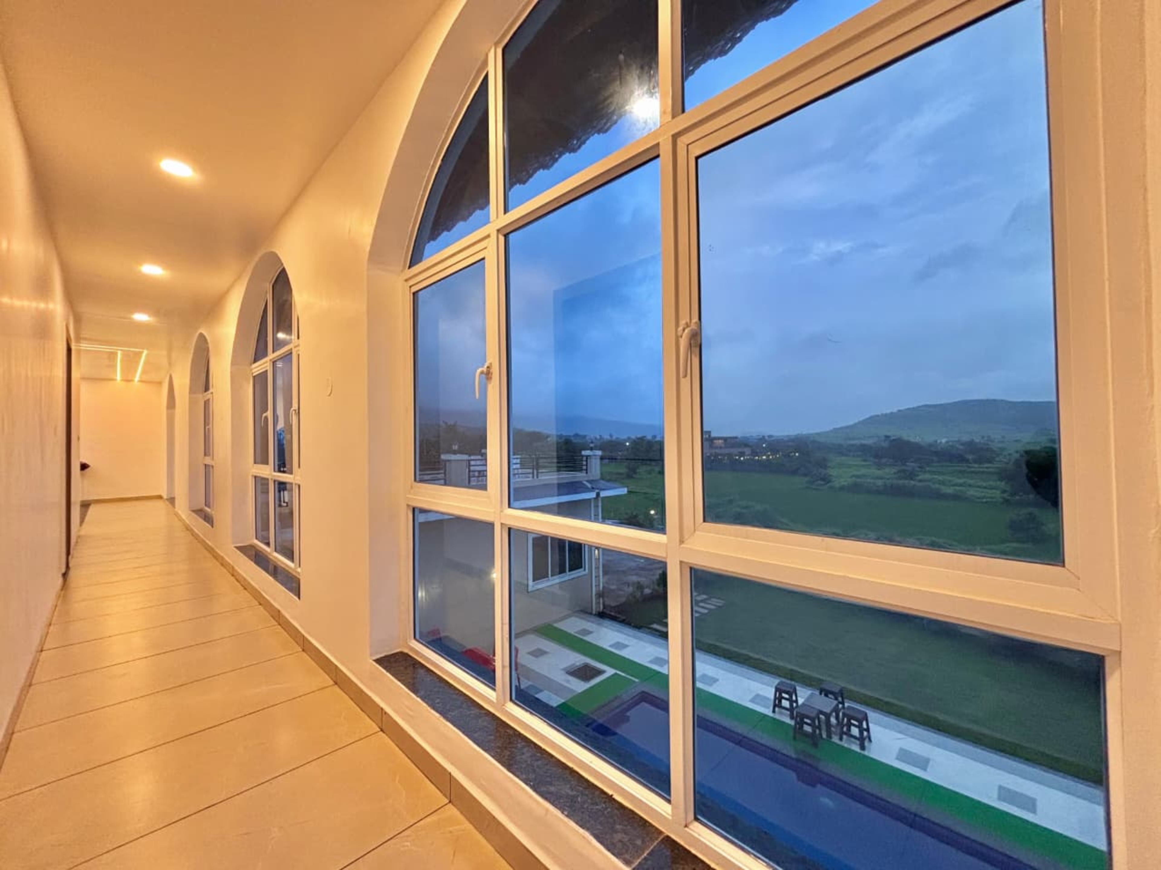 A corridor with large windows offering a view of a green landscape and distant hills.