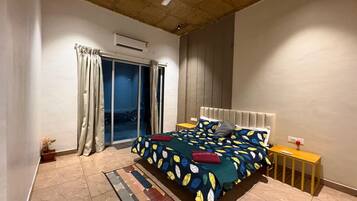 A bedroom with a bed, a nightstand, a ceiling fan, and a view through a sliding door.