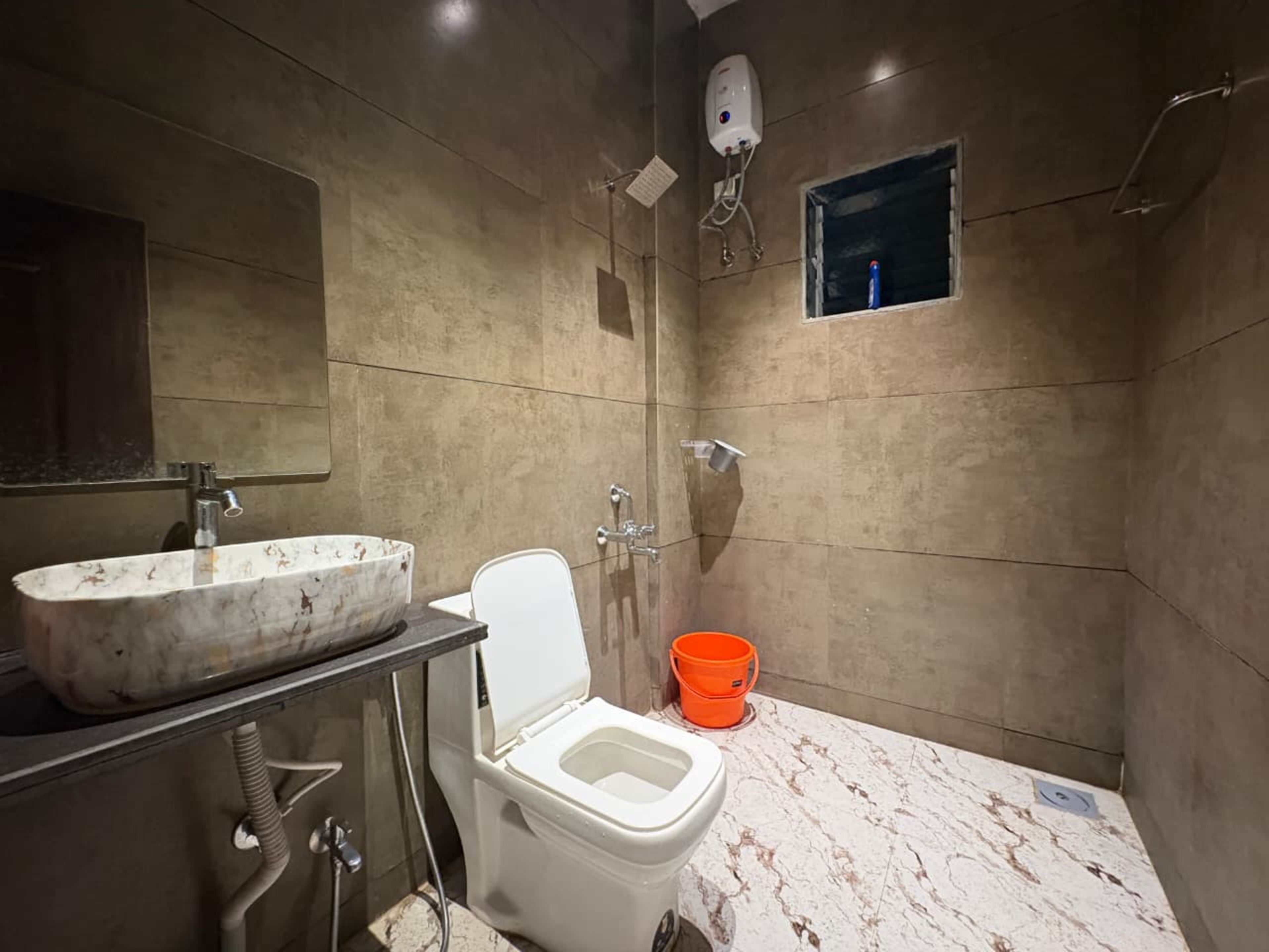Un baño con lavamanos de mármol, inodoro y ducha.