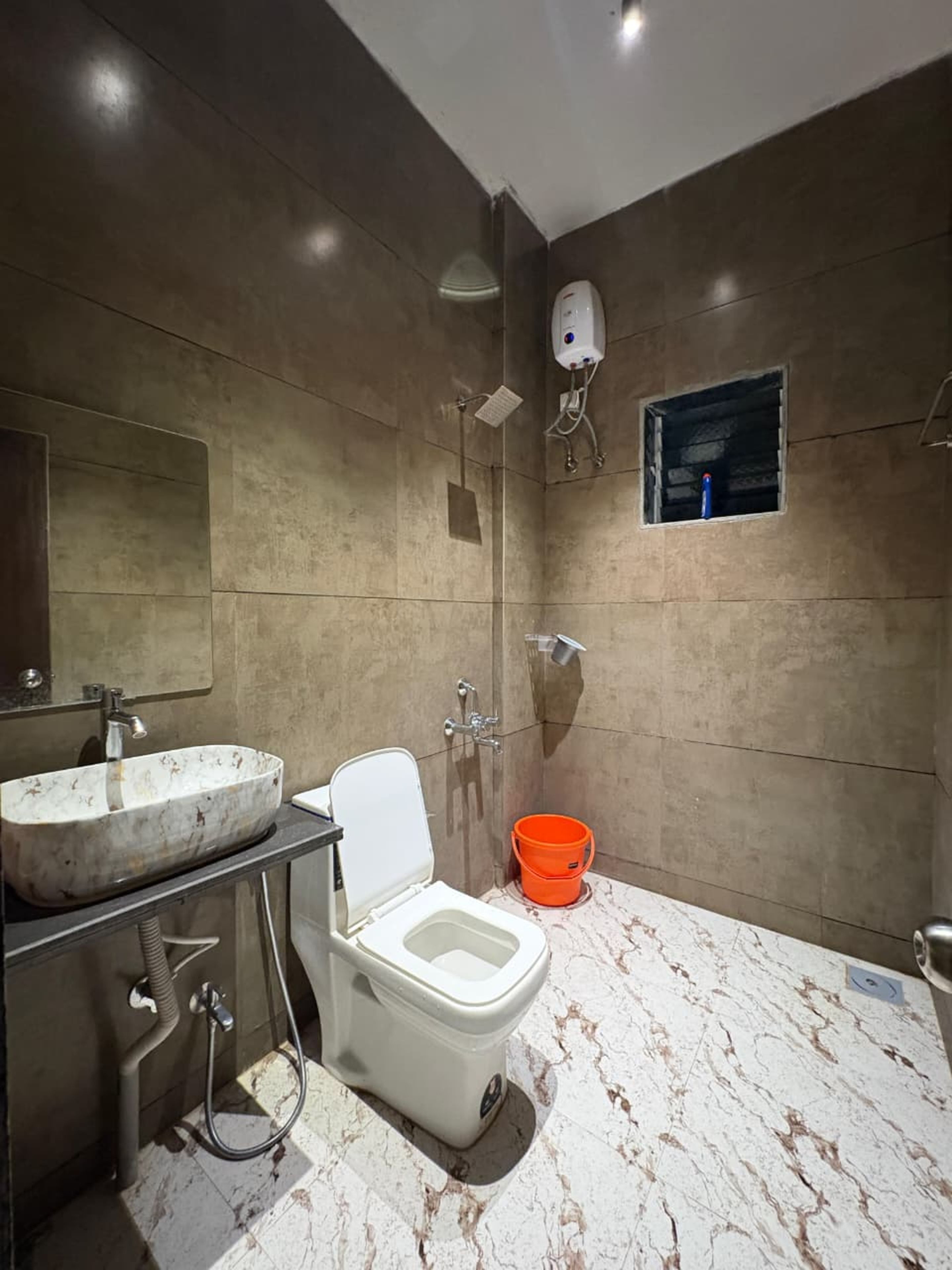 A modern bathroom with a marble sink, a toilet, and a shower area.
