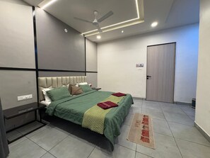 Une chambre d’hôtel avec un lit, un ventilateur de plafond, une porte et un panneau indiquant qu’il est interdit de fumer.