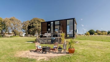Una casa moderna con terraza, mobiliario exterior y césped.