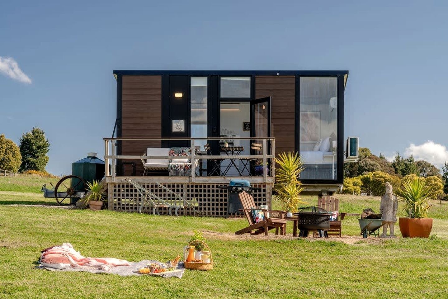 A modern house with a deck, outdoor furniture, and a picnic setup.