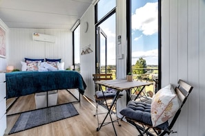 Une chambre avec un lit, une petite table et une chaise, un balcon avec vue et une fenêtre.