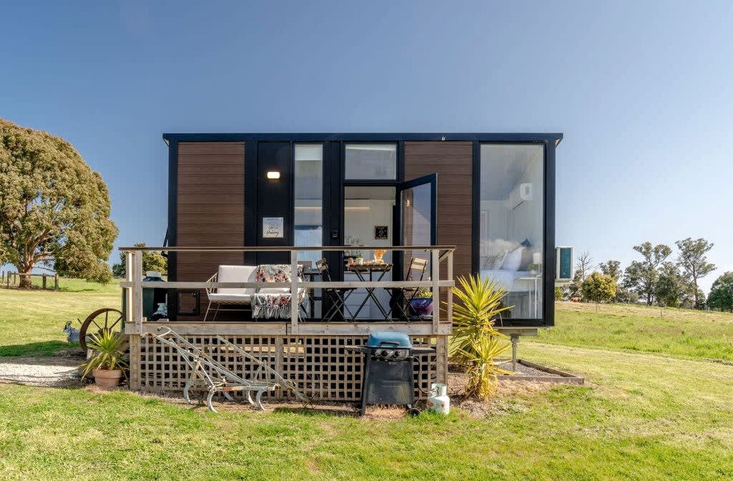 A modern cabin with a deck, outdoor seating, and a large window.
