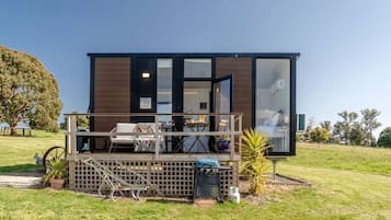 A modern cabin with a deck, outdoor seating, and a large window.