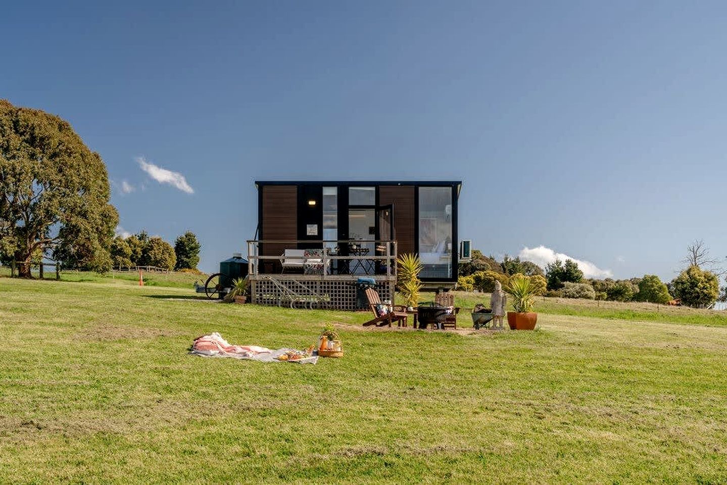 Ein modernes Haus mit einer Terrasse, umgeben von einer grünen Wiese und Bäumen.