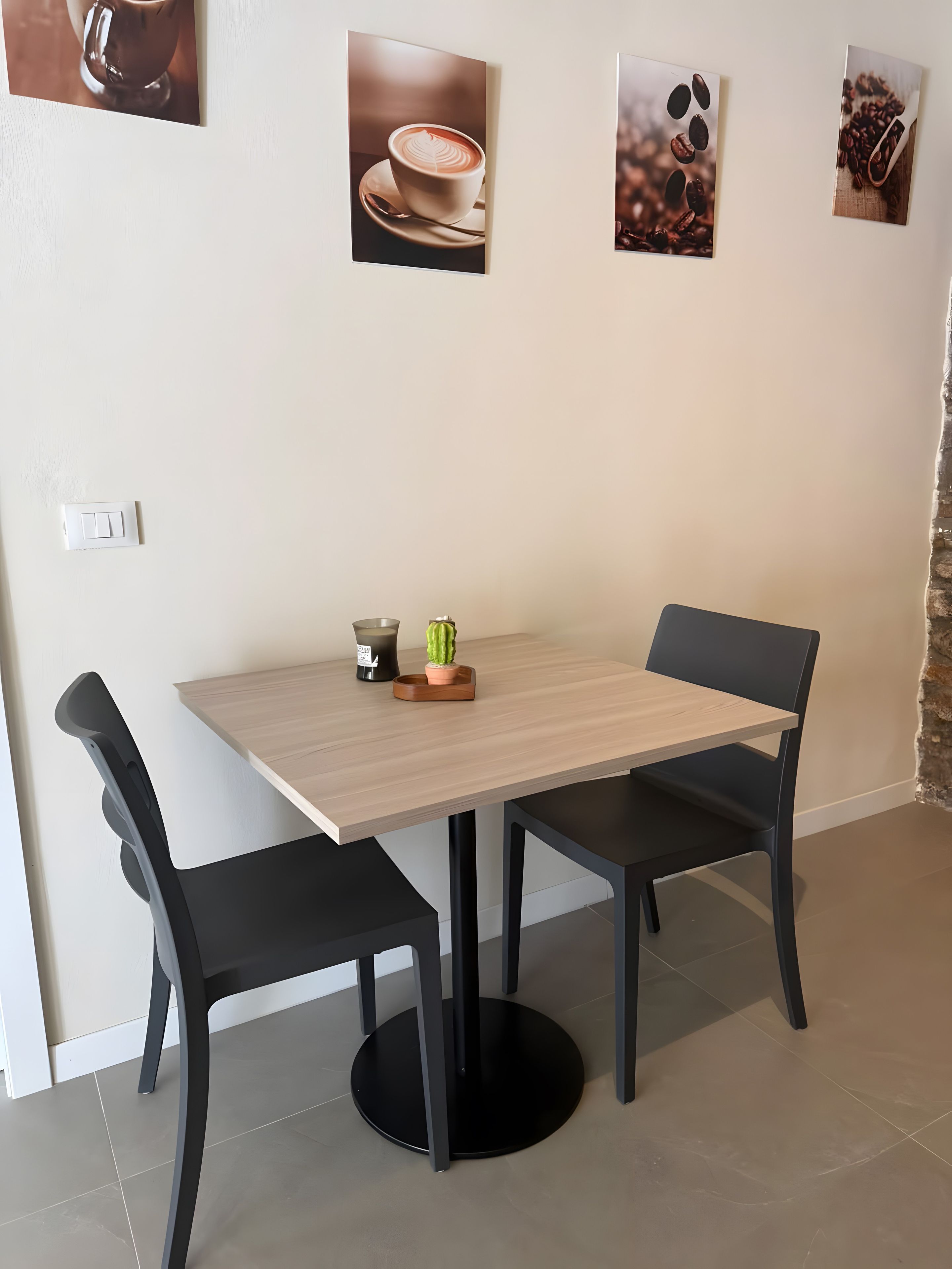A dining area with a table and chairs, a potted plant, and a wall-mounted light switch.