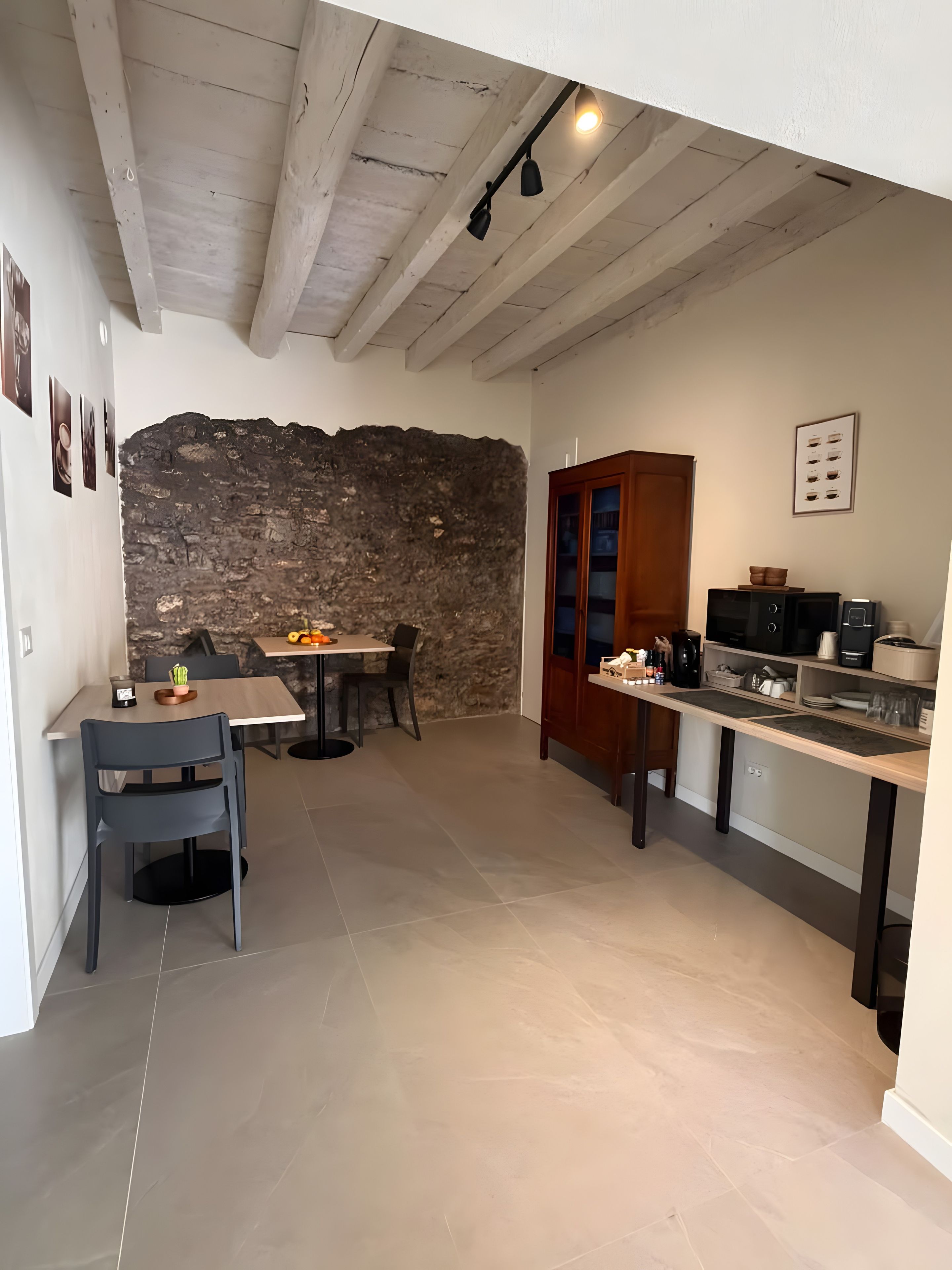 A compact kitchen with a stone wall, wooden cabinets, and a dining area with chairs and a table.