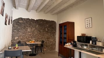 Eine kompakte Küche mit Steinwand, Holzschränken und einem Essbereich mit Stühlen.