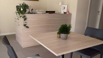 Un espace repas moderne avec une table en bois, deux chaises, une plante en pot et un tableau encadré au mur.
