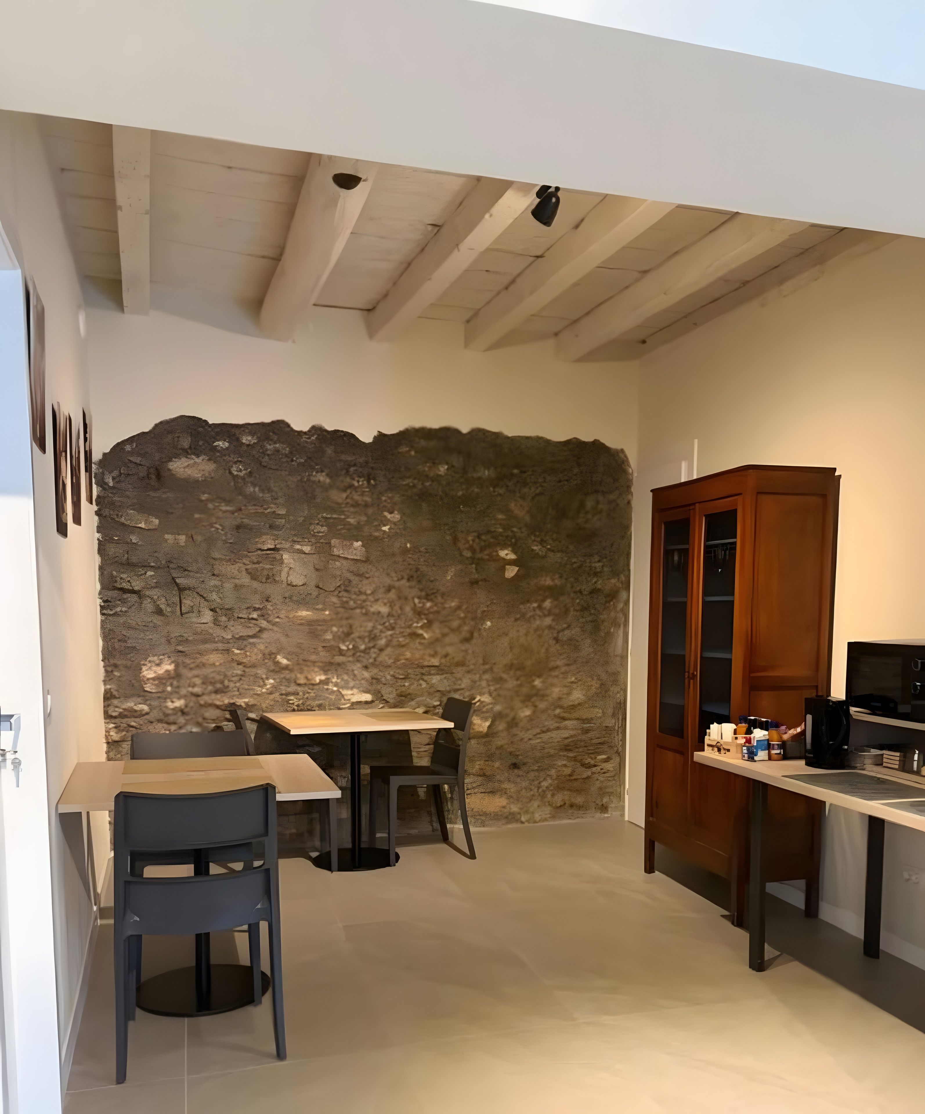 Una cucina compatta con parete in pietra, zona pranzo con sedie e un armadietto in legno.