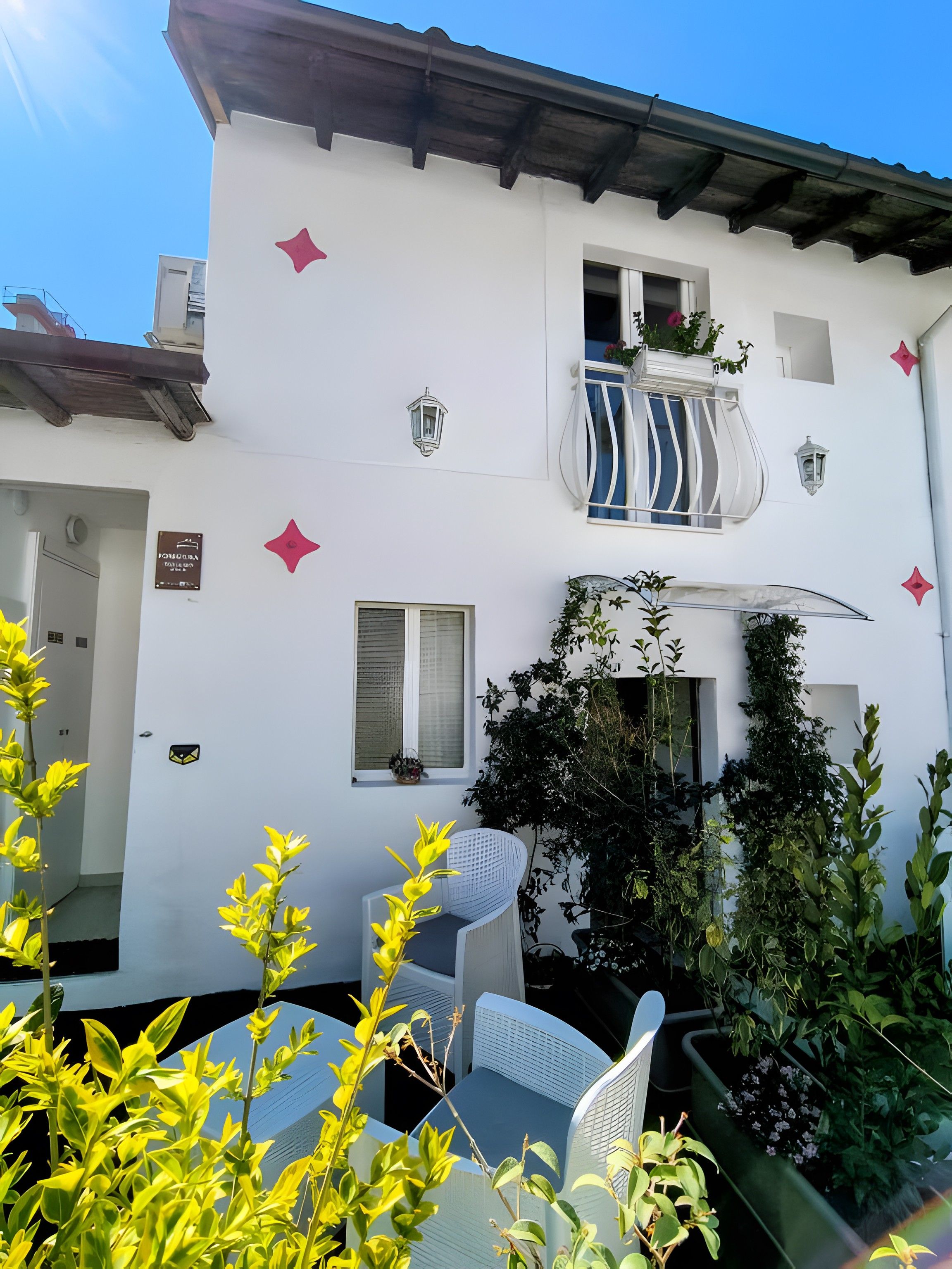 Un edificio bianco con balconi, una porta e piante in vaso.