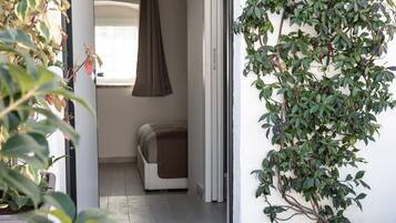 A doorway leading to a room with a bed, a hanging light fixture, and a potted plant.