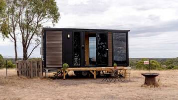 A mobile home with a sliding door, a small table, and a fire pit.