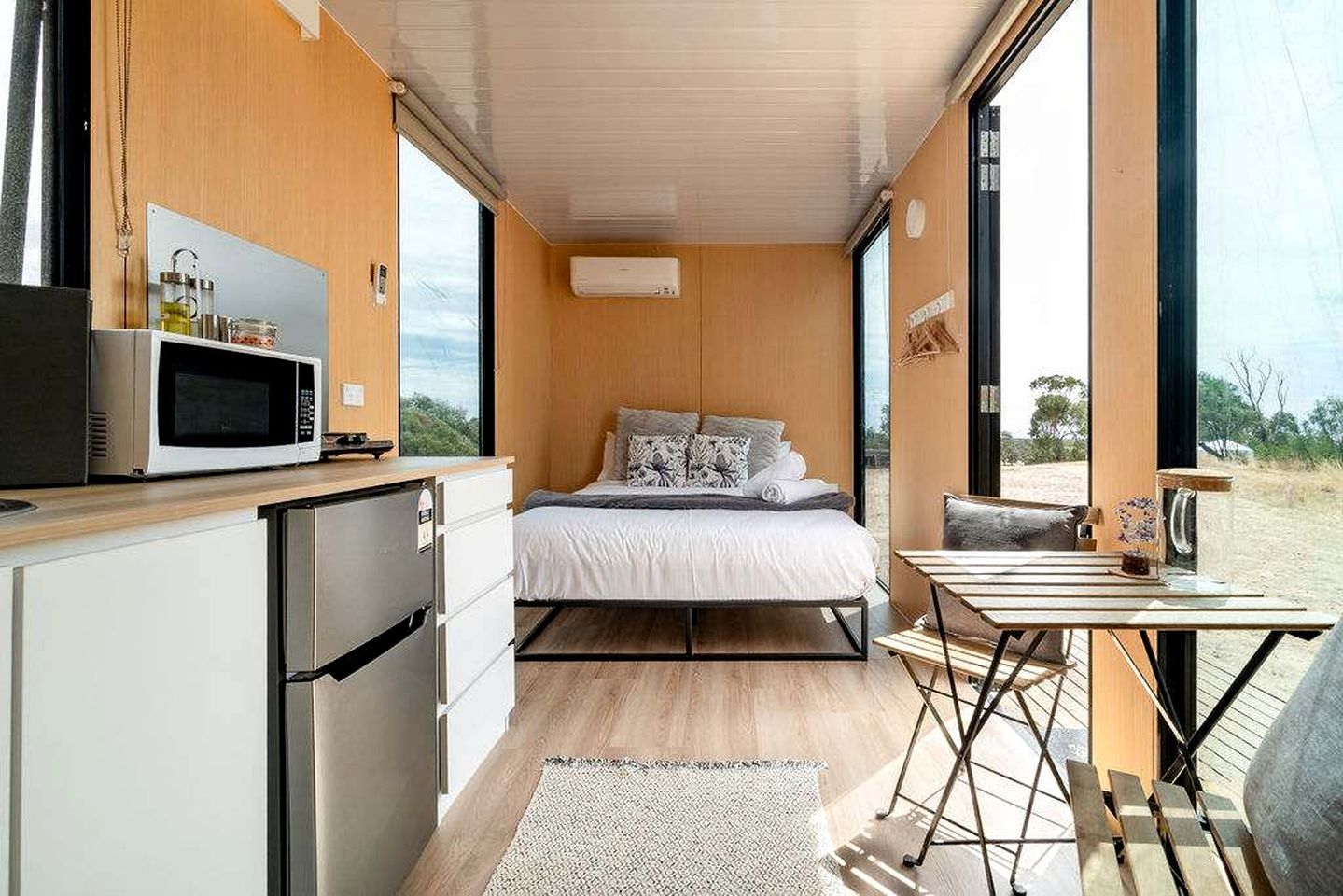 A compact bedroom with a bed, bedside table, and a view of the outdoors.
