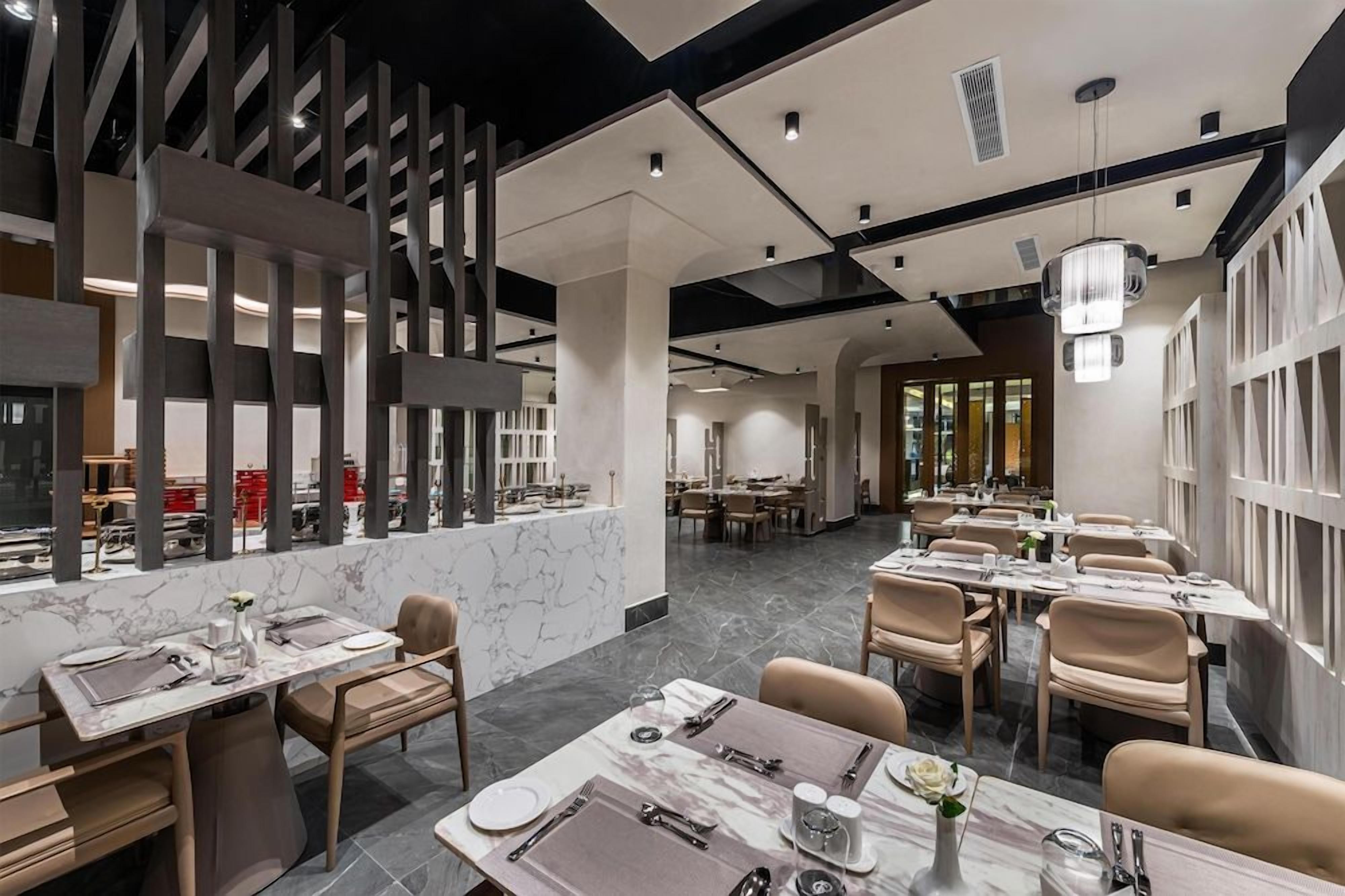 Un interior de restaurante moderno con suelo de mármol, techos altos y mobiliario contemporáneo.