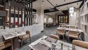 Un interior de restaurante moderno con suelo de mármol, techos altos y mobiliario contemporáneo.