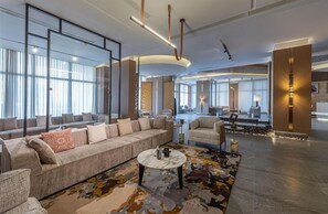 A spacious hotel lobby with a large sofa, a coffee table, and a patterned rug. - Grand Plaza Tabuk (Tabuk)