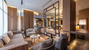 Un lobby moderno de hotel con zona de estar, un mostrador de recepción y un gran espejo que refleja el interior.