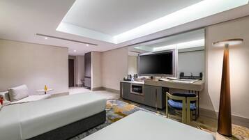 Habitación de hotel con cama, escritorio con televisor de pantalla plana, espejo y lámpara.