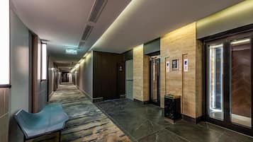 Un pasillo de hotel con piso alfombrado, un banco y un basurero.