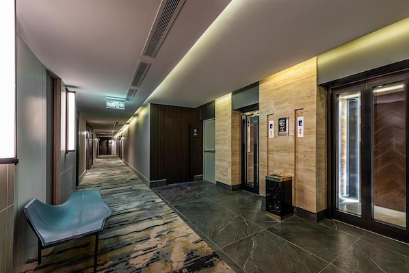 A hotel corridor with a carpeted floor, a bench, and a trash bin. - Grand Plaza Tabuk (Tabuk)