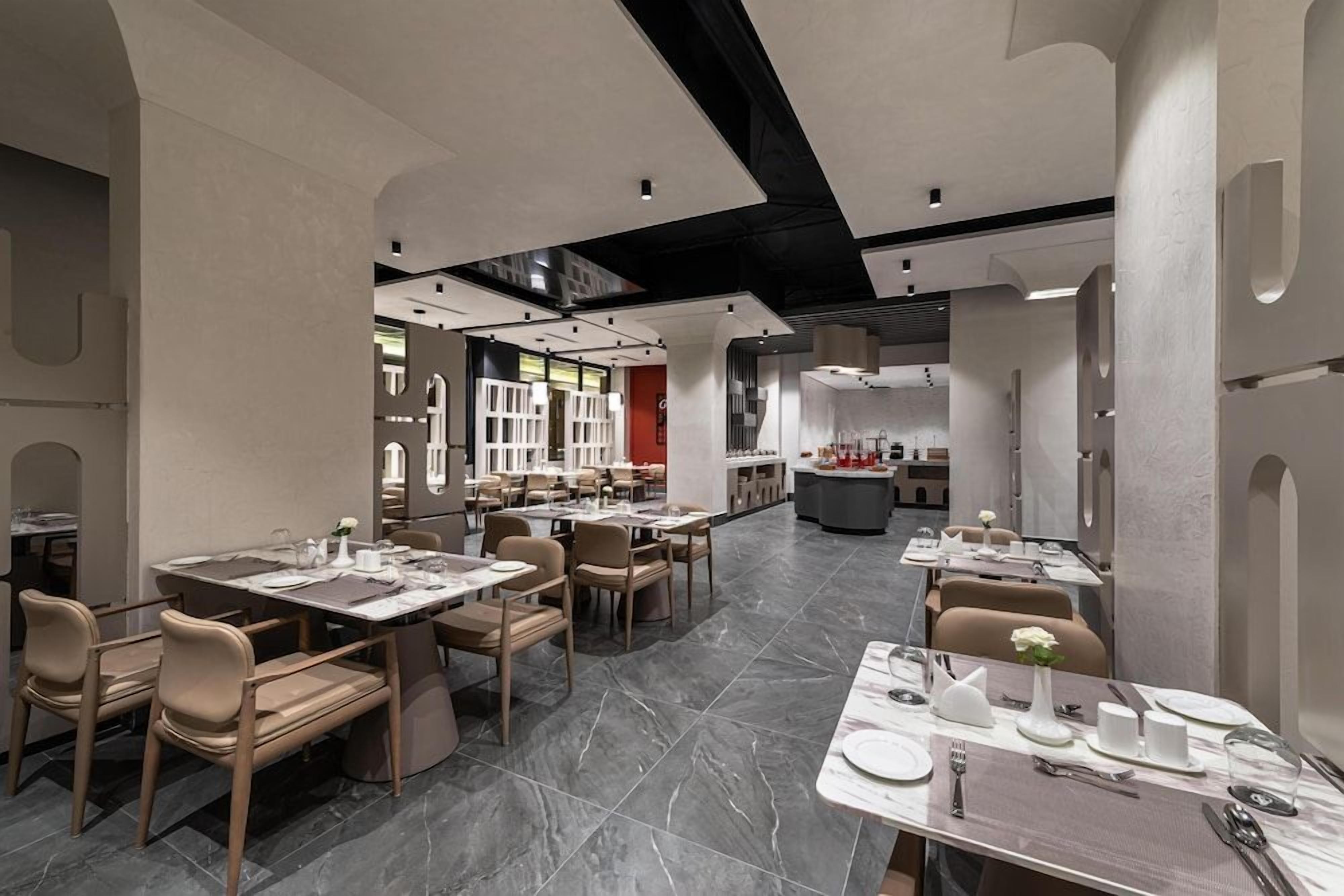 Un interior de restaurante moderno con suelo de mármol, varias mesas de comedor y sillas.