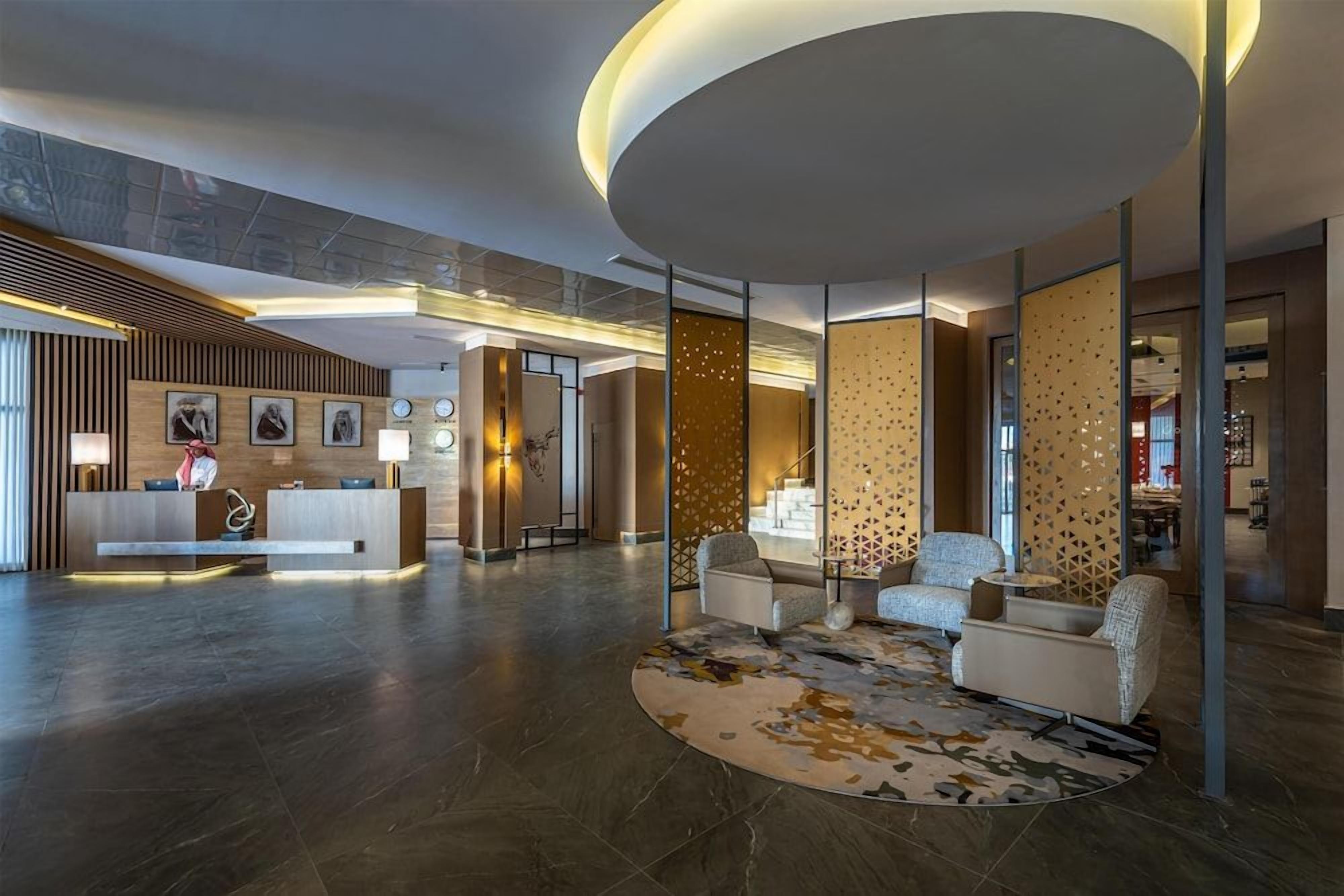 Un vestíbulo moderno con mostrador de recepción, zona de estar y paneles decorativos.