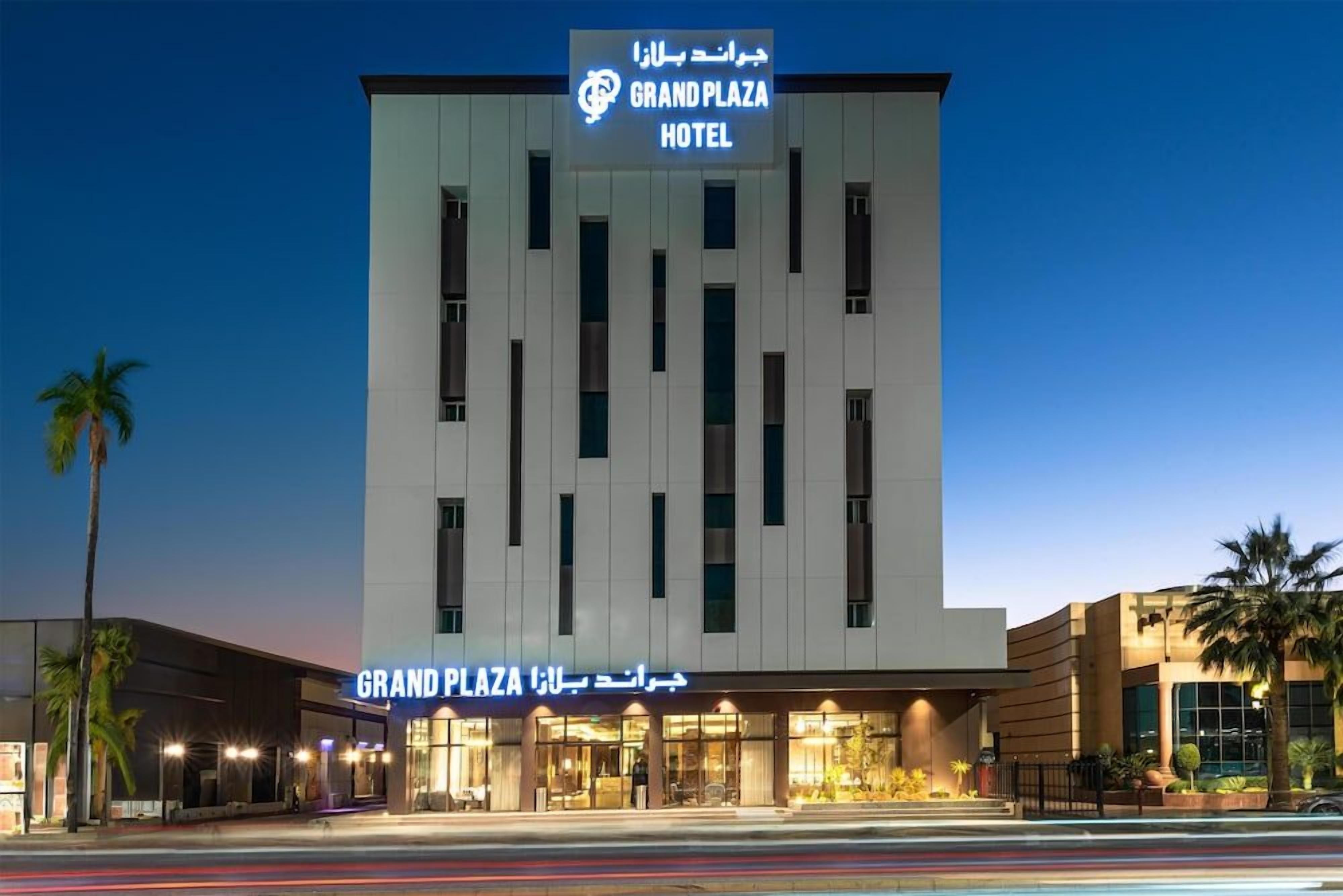 Un hotel con fachada moderna, señalización en varios idiomas y una entrada bien iluminada.