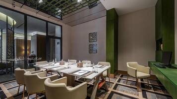 Una sala de conferencias moderna con un panel de vidrio, una mesa larga con sillas y una pared de acento verde.