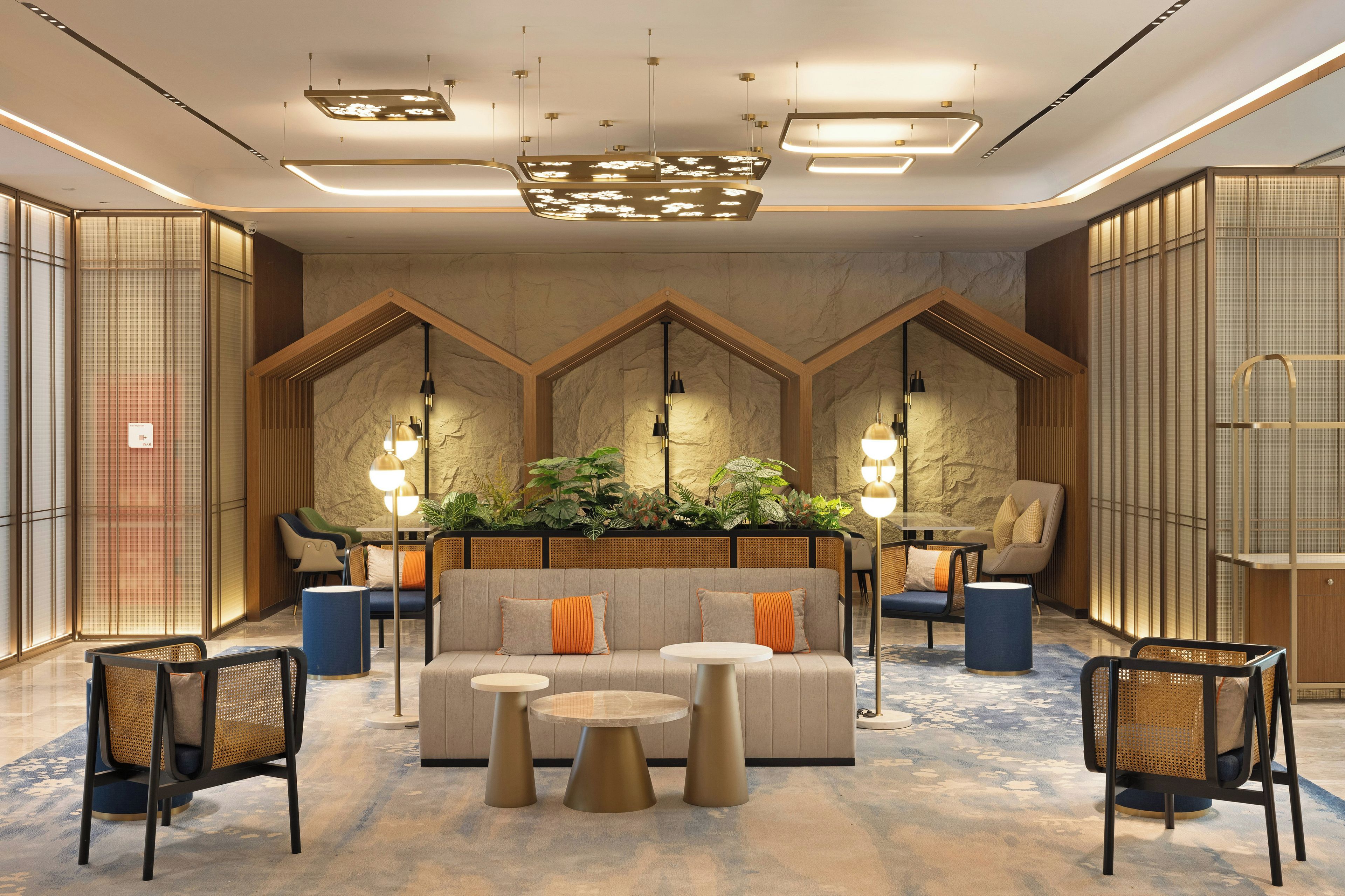 A modern lobby with a central seating area, multiple light fixtures, and a decorative plant arrangement.