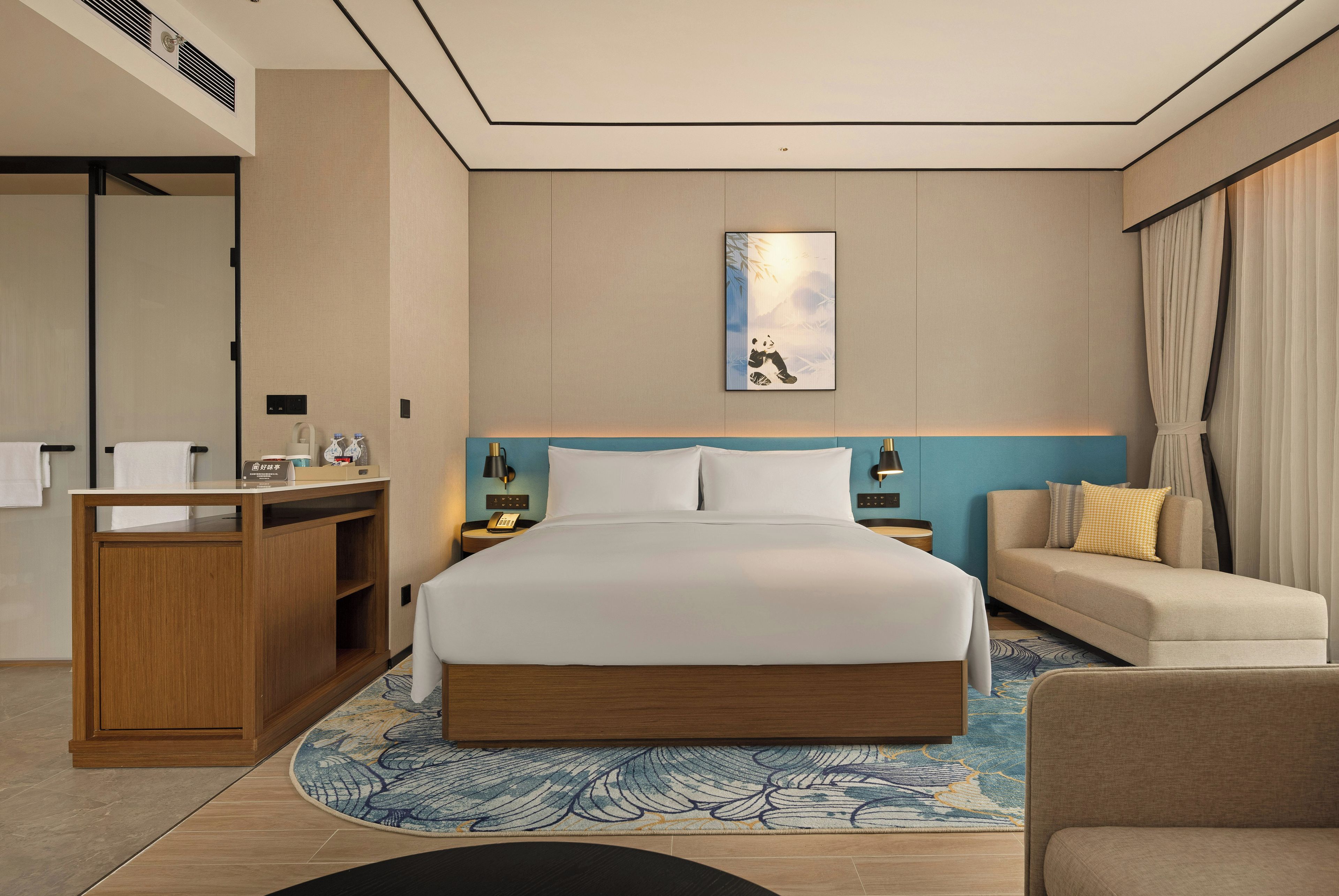 Una habitación de hotel con una cama, un escritorio, un sofá y una obra de arte colgada en la pared.