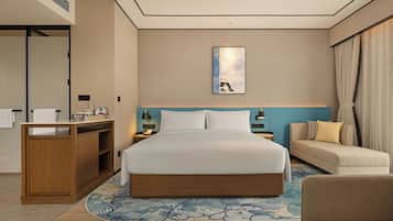 Una habitación de hotel con una cama, un escritorio, un sofá y una obra de arte colgada en la pared.